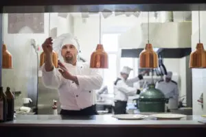 Chef preparing pasta in a professional kitchen.